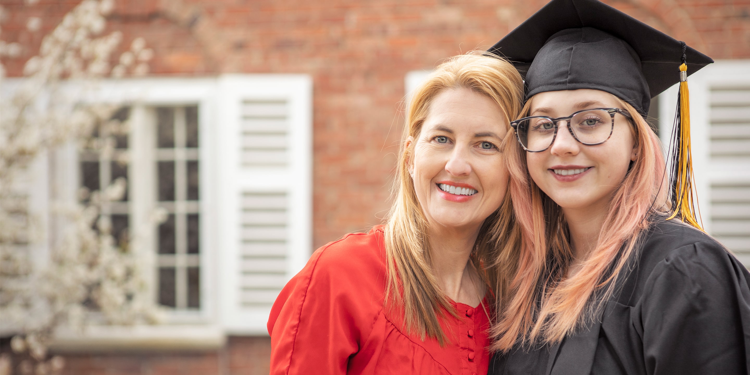 Daughter in graduation cap and gown with her mother