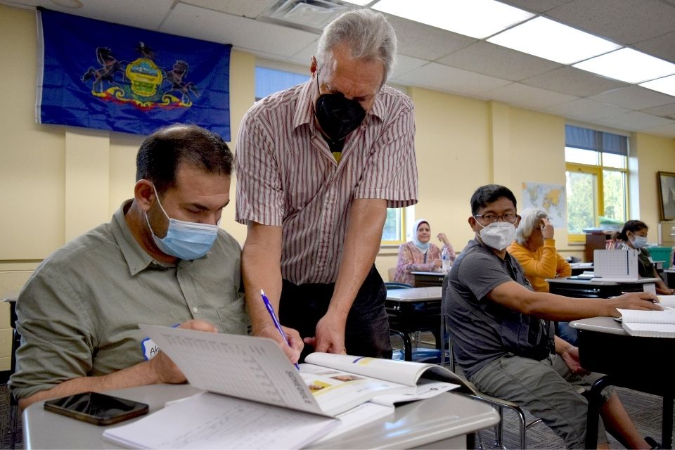 A volunteer helps a student learn English